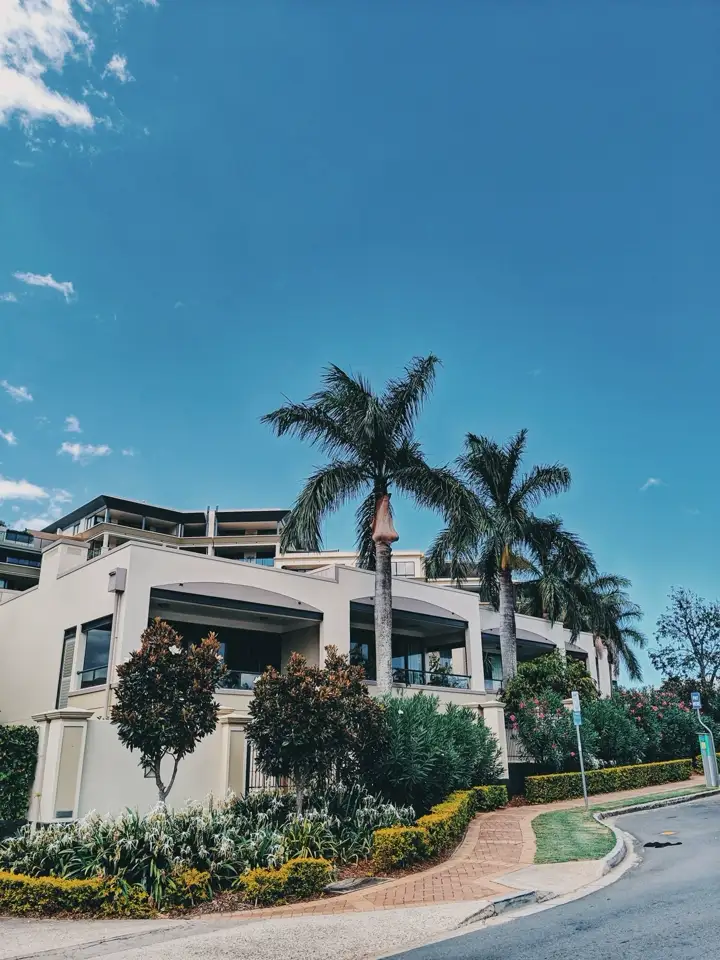 A cream residence framed by palm trees and a curved street