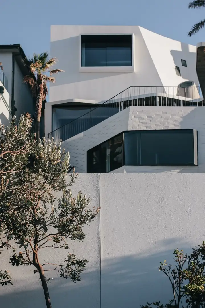 A white, sculptural home stepping down a hillside